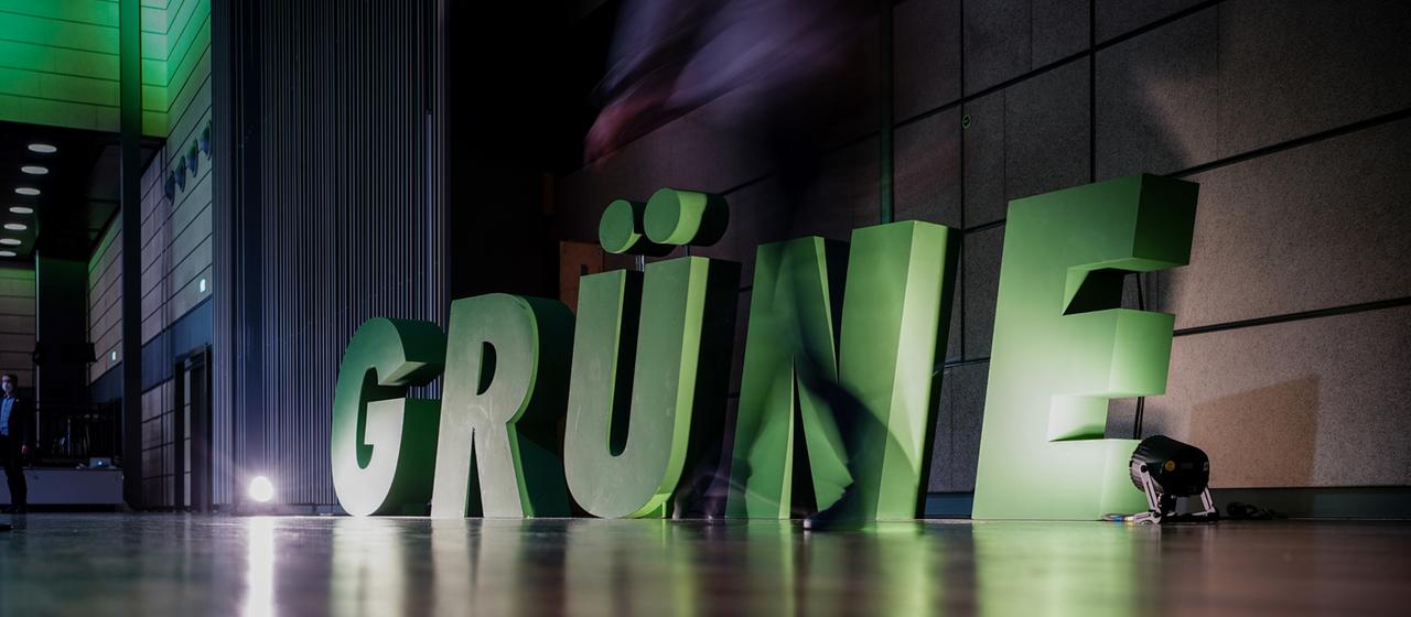 Ein Delegierter geht beim Bundesparteitag von Bündnis 90/Die Grünen am Logo seiner Partei vorbei.