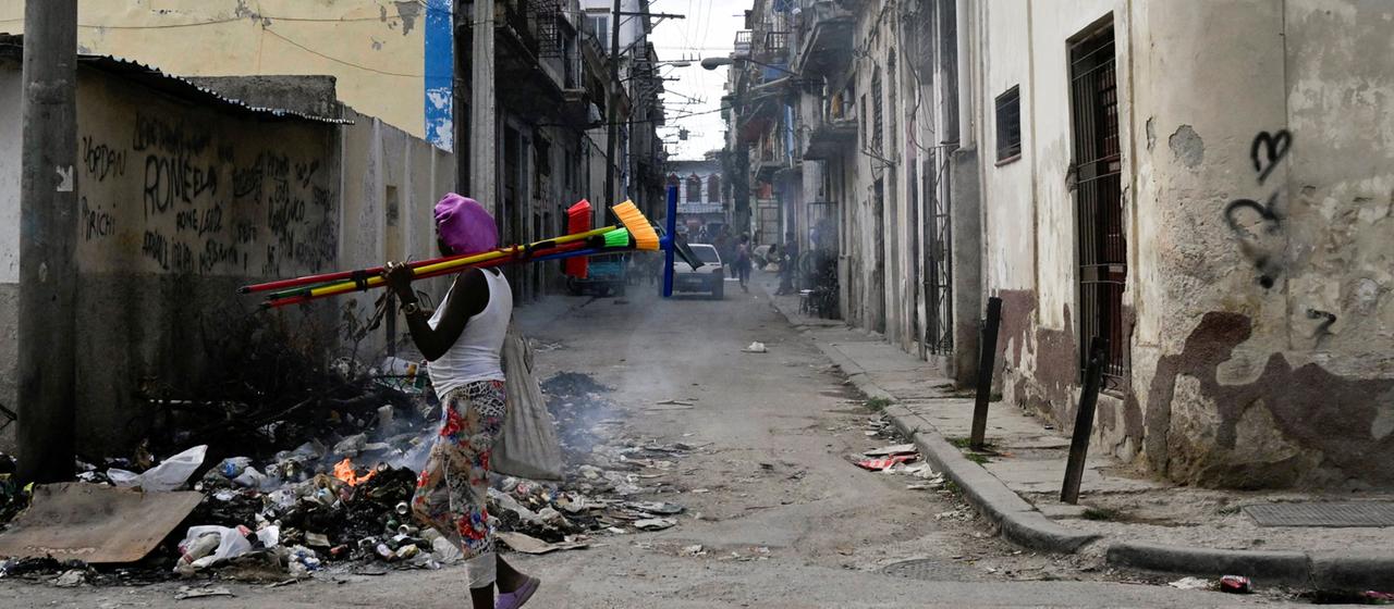 Ein Straßenverkäufer geht an einem brennenden Müllhaufen in Havanna vorbei.